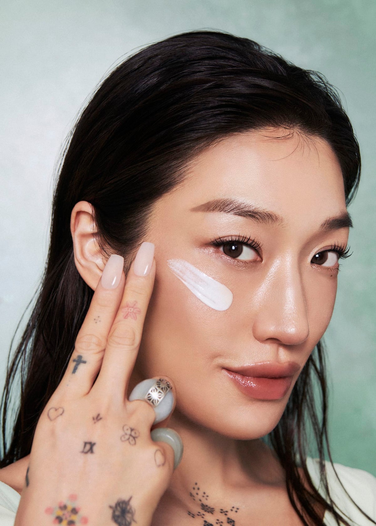 a woman with a hand gesture and a white cream on her face