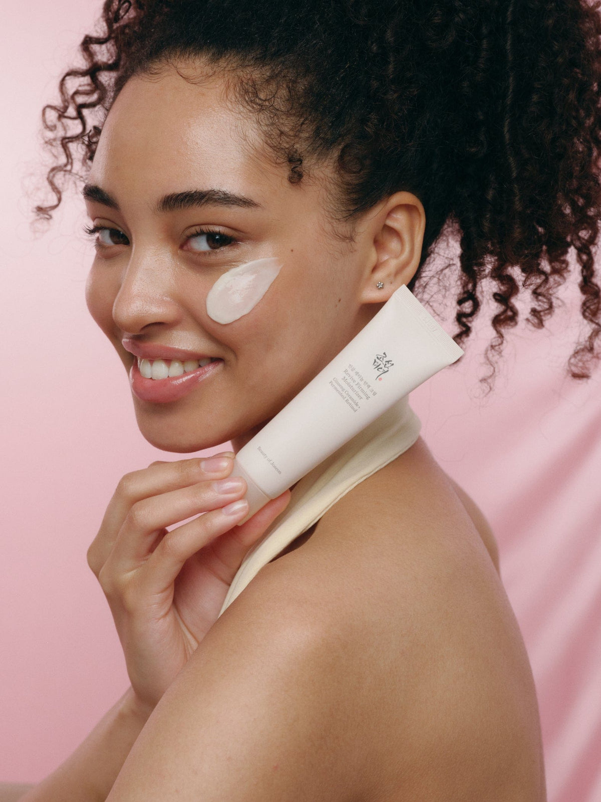 a woman holding a tube of cream