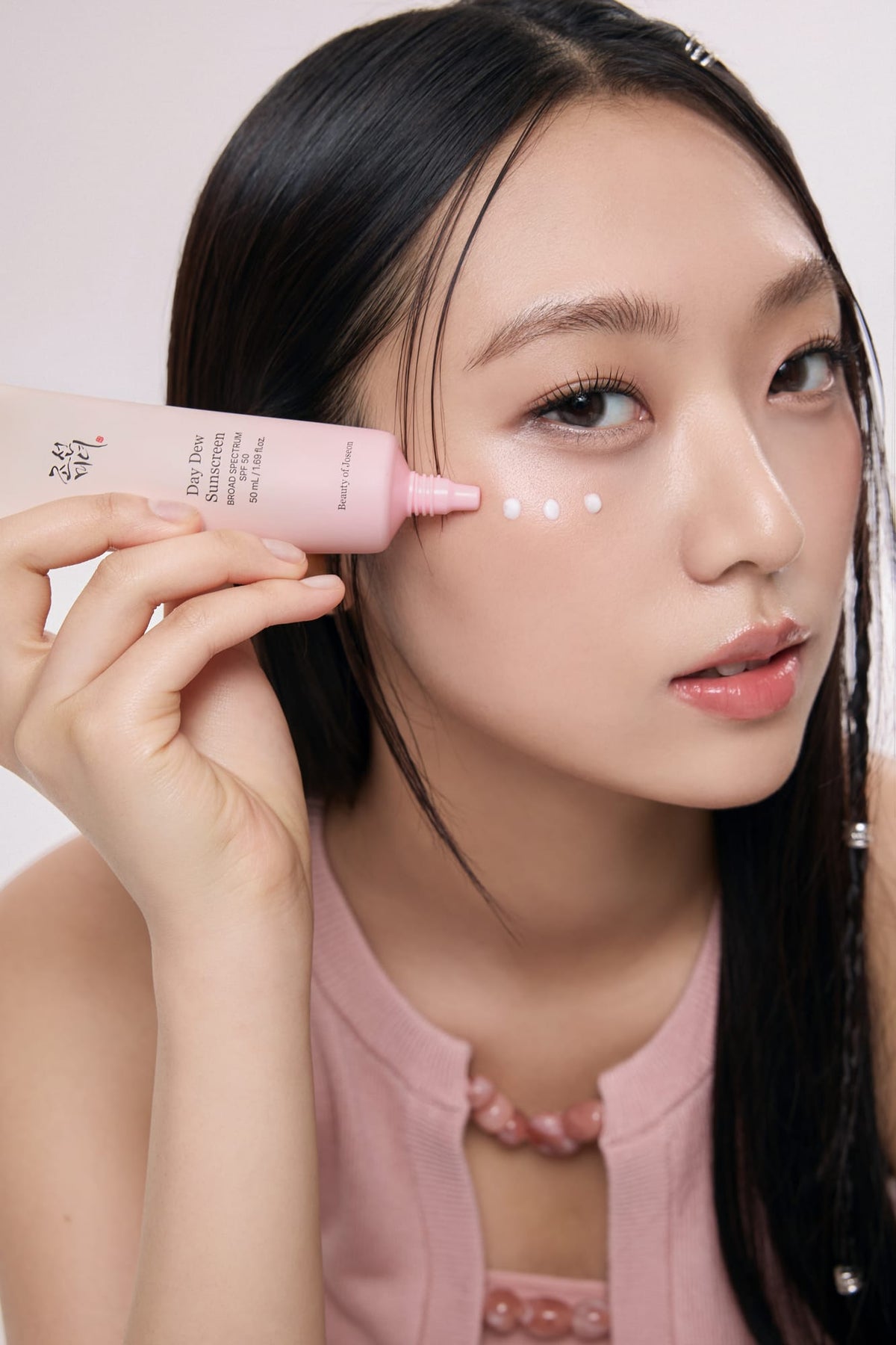 a woman holding a tube of cream on her face