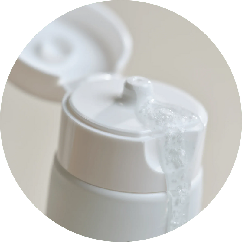 a white bottle with a foaming liquid coming out of it
