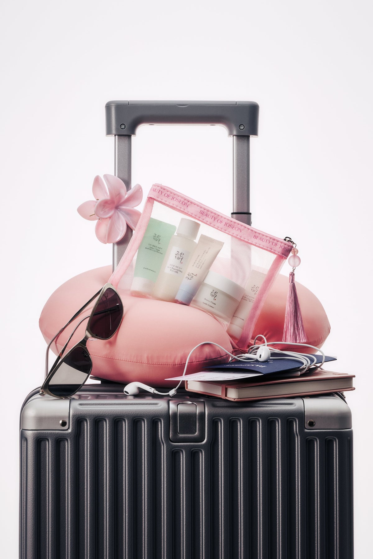 a suitcase with a pink bag and sunglasses on top