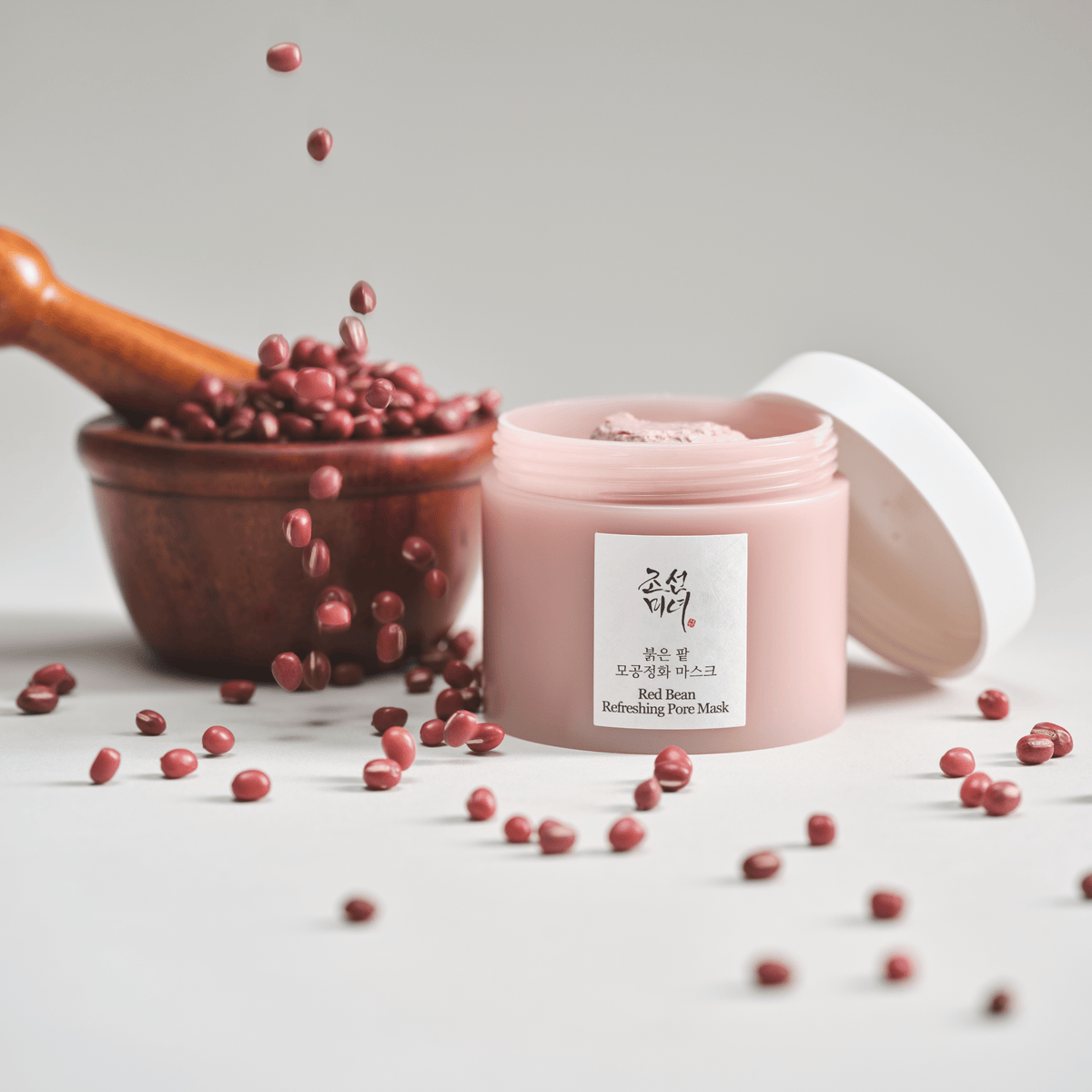 a jar of pink cream next to a bowl of red beans