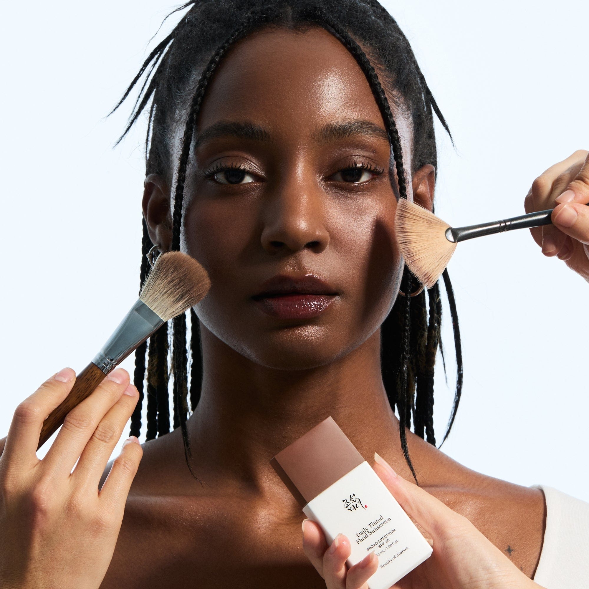 a woman holding brushes and a box of makeup