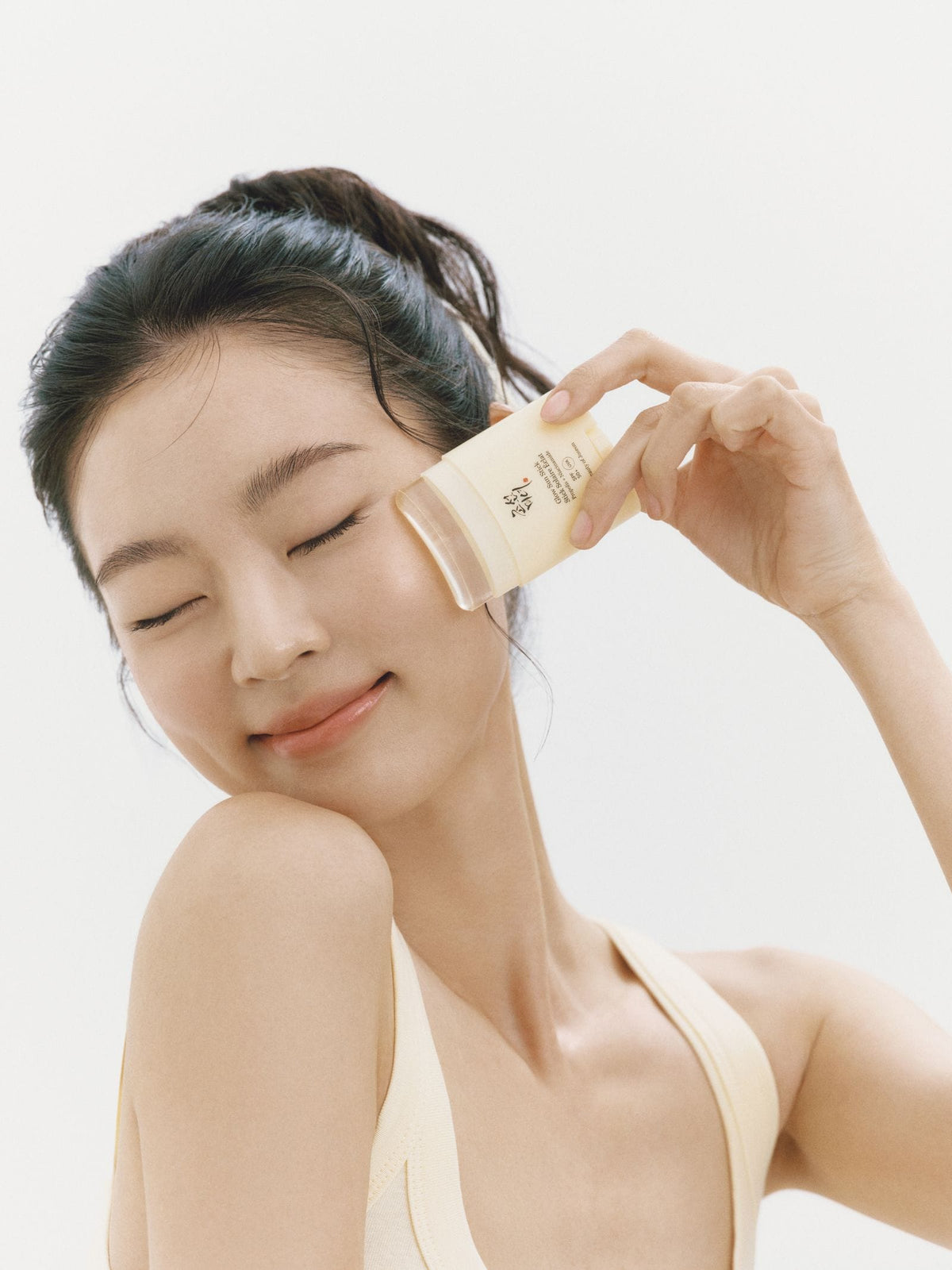 a woman holding a small container of cream on her face