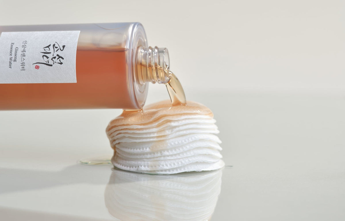 a bottle of liquid pouring out of a bottle onto a stack of cotton pads