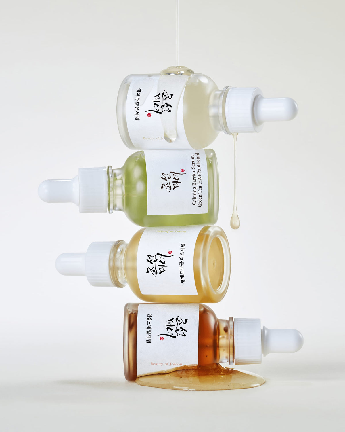 Four skincare serum bottles with droppers on a white background