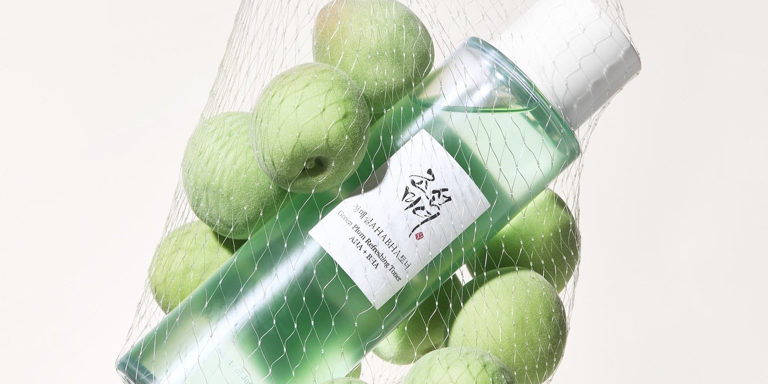 a bottle of liquid in a net bag with apples
