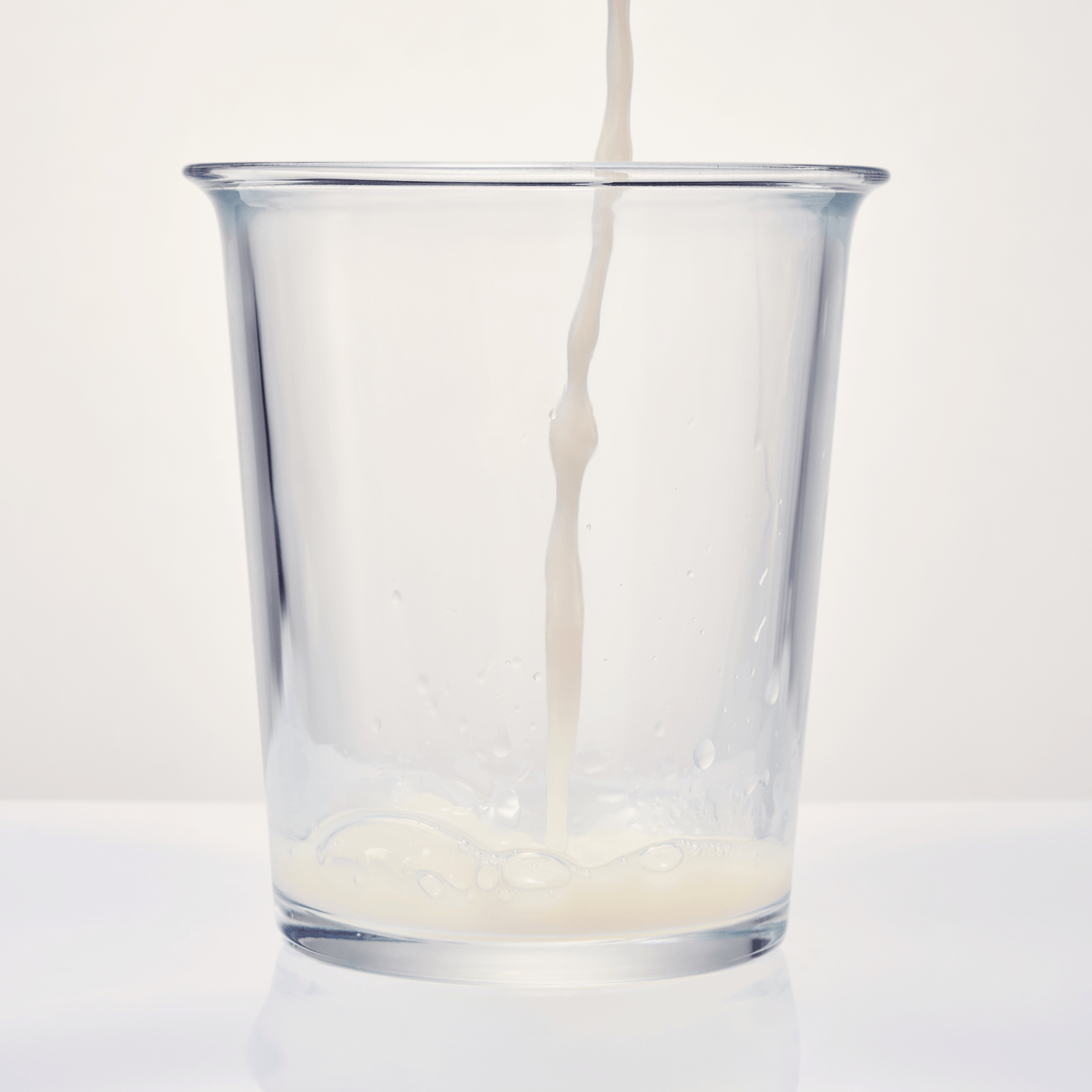 For clinical tests - Glass being filled with milk on a white background