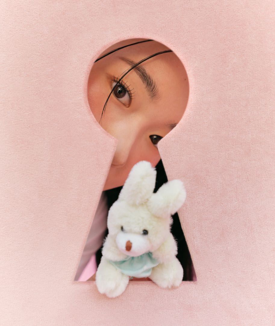 a woman looking through a keyhole with a stuffed animal