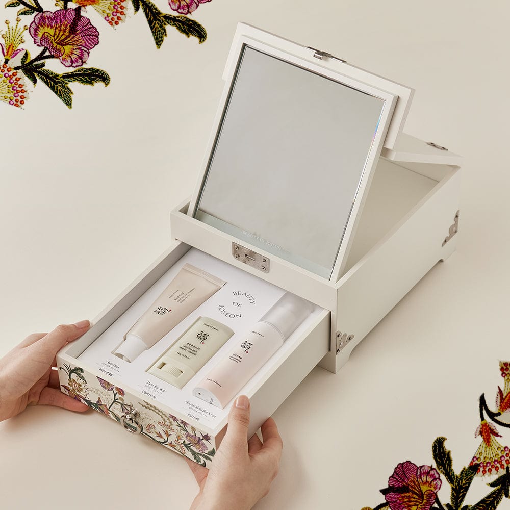 a hand holding a box with a mirror and a small white box with a white lid
