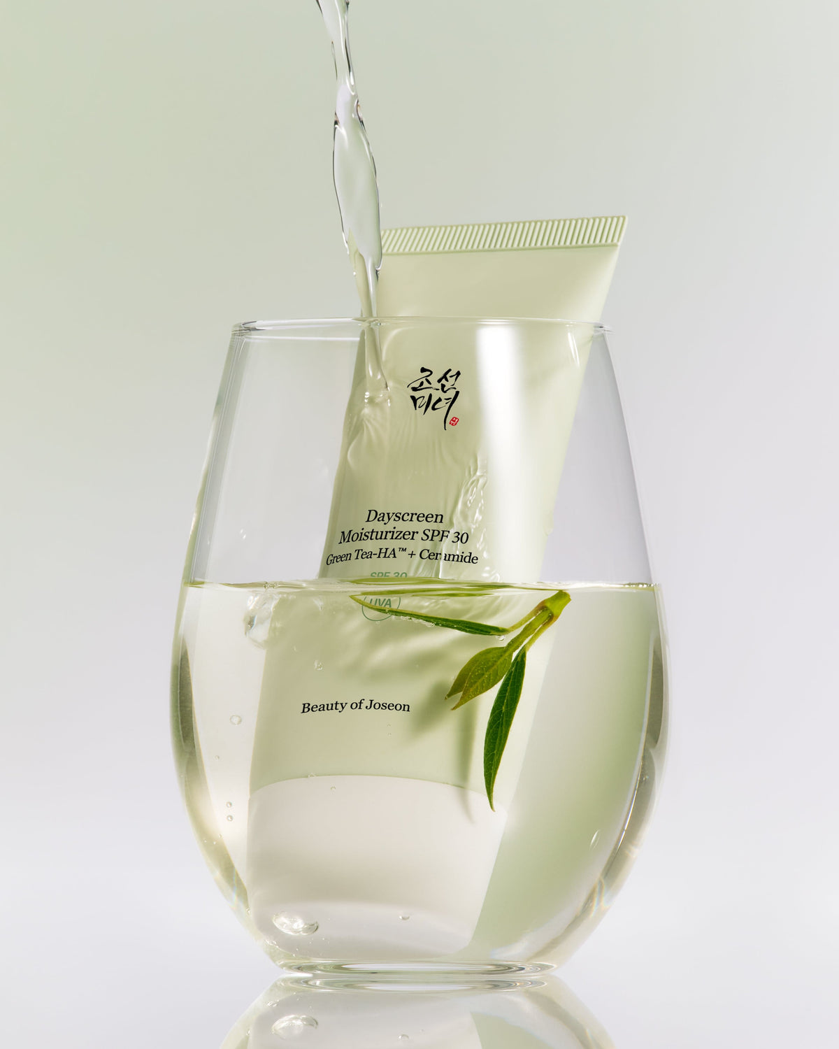 a glass of water with a tube of liquid and leaves