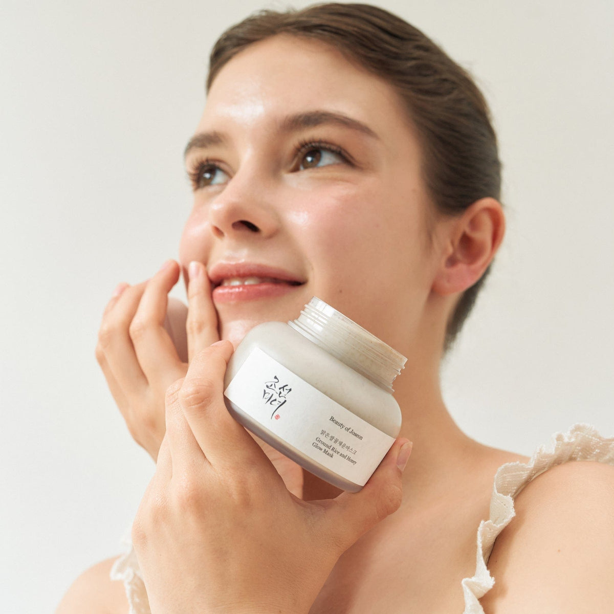 a woman holding a jar of cream