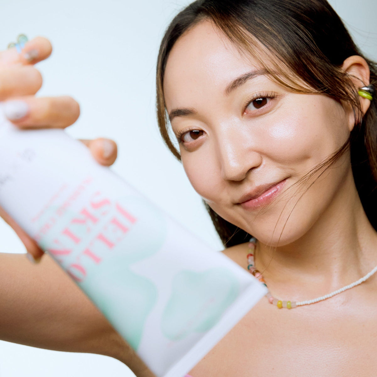 a woman holding a tube of skin care product