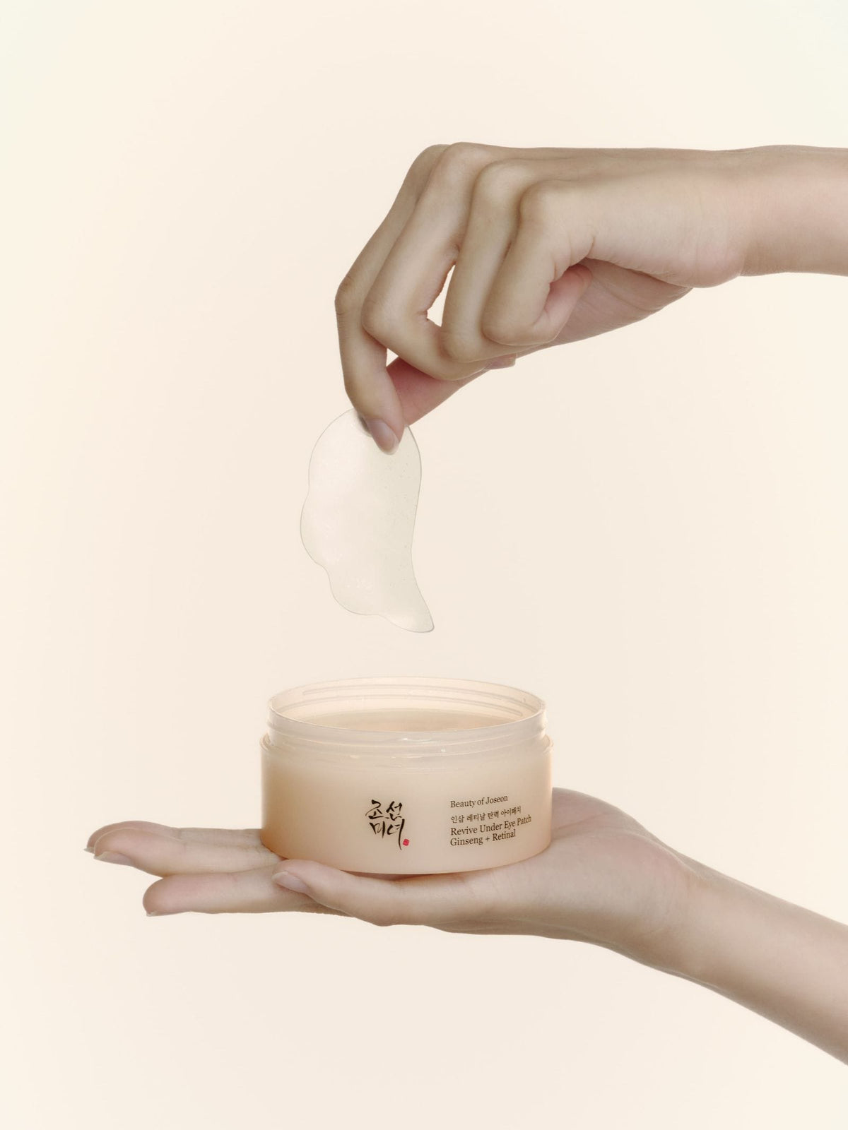 Hand holding a jar of Revive Under Eye Patch: Ginseng + Retinal with a white background