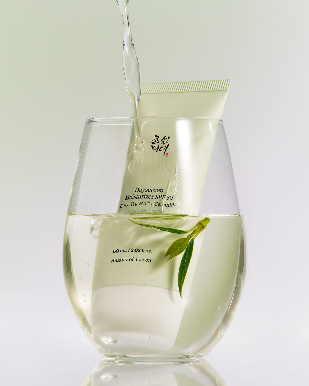 a glass of liquid with a tube of cream in it